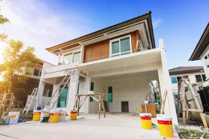 A large house surrounded by ladders and paint buckets.